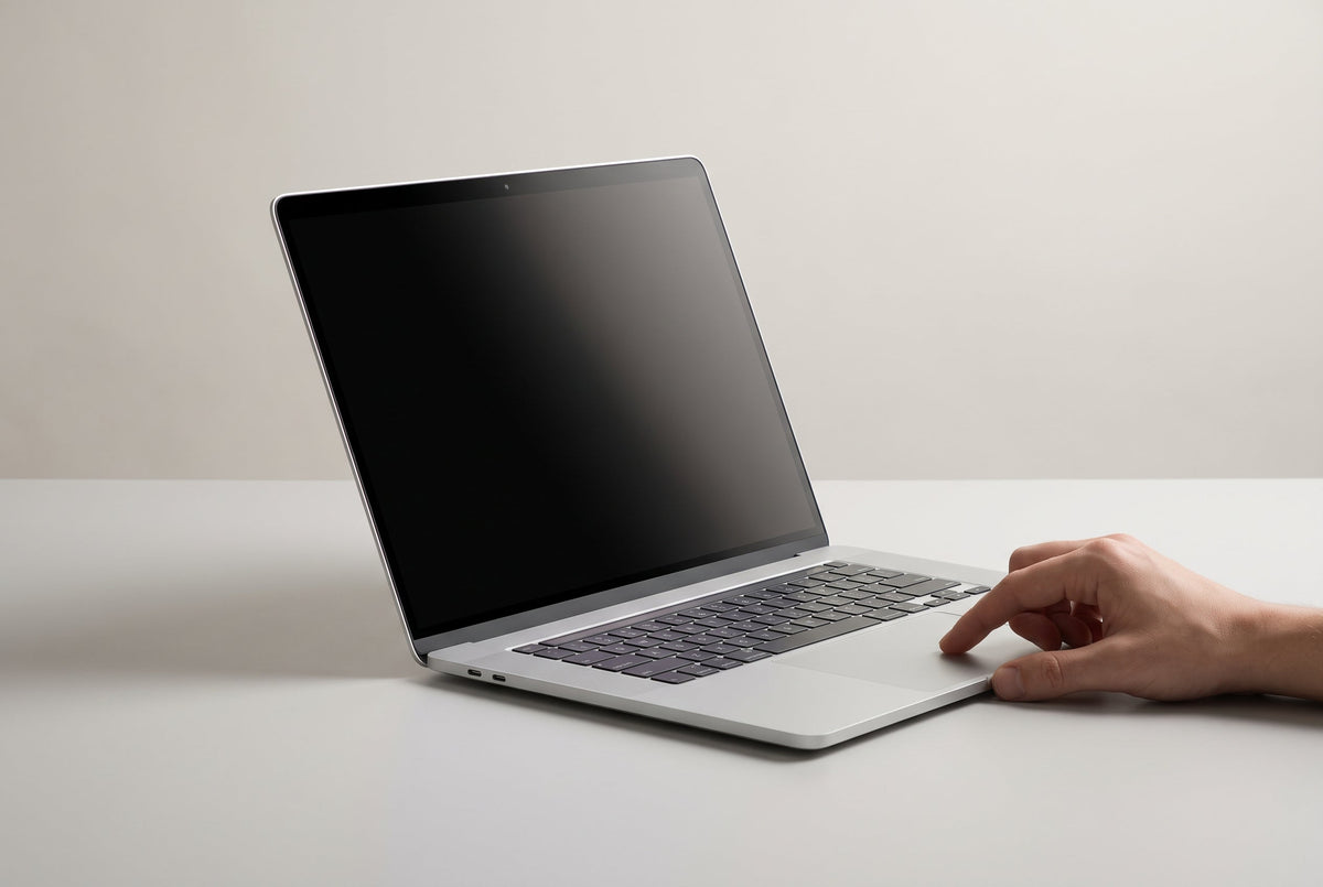 Persoon werkt op een MacBook in een trein terwijl het scherm vanaf de zijkant verduisterd is
